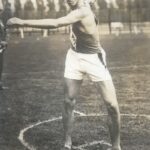Black and white image of male athlete throwing a discus