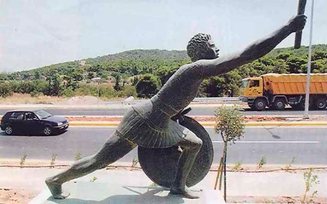 Bronze statue of a male runner of Ancient Greece holding out and olive branch in his right hand and resting on his shield with his left hand